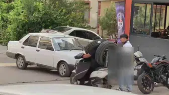 Otomobil lastiğini boynuna asan kuryenin dikkat çeken taşıma yöntemi